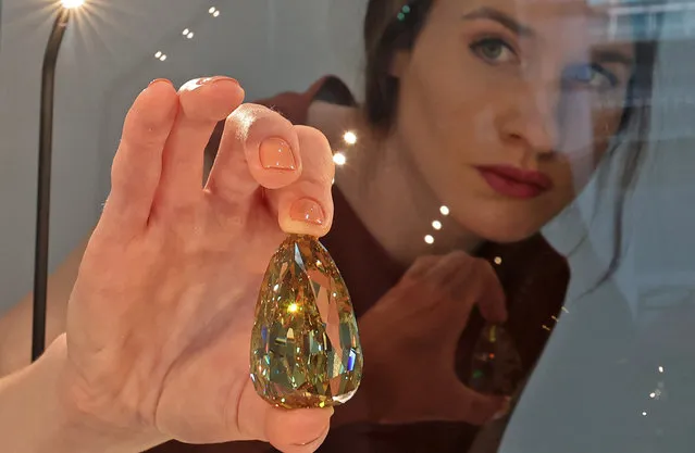 An employee picks up the “Golden Canary” brownish-yellow coloured diamond, weighing 303.10 carats, at Sotheby's in the Gulf emirate of Dubai on October 17, 2022. (Photo by Giuseppe Cacace/AFP Photo)