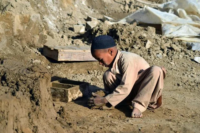 A child makes clay bricks with a mould at a brick kiln in Kandahar on November 11, 2021. (Photo by Javed Tanveer/AFP Photo)
