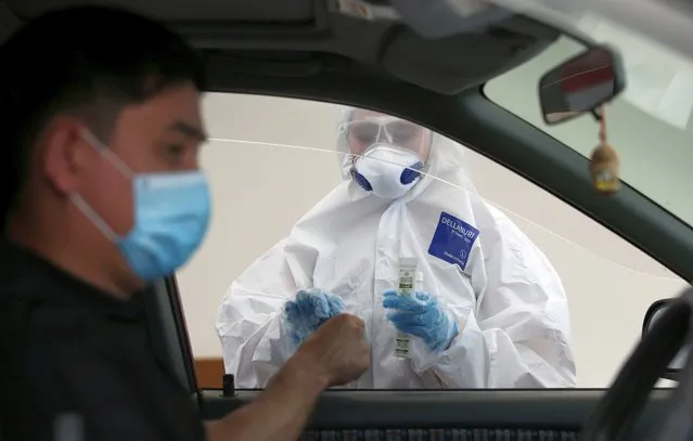 A health worker approaches a car driver at a mobile testing station for the coronavirus disease (COVID-19) in Almaty, Kazakhstan on June 17, 2020. (Photo by Pavel Mikheyev/Reuters)