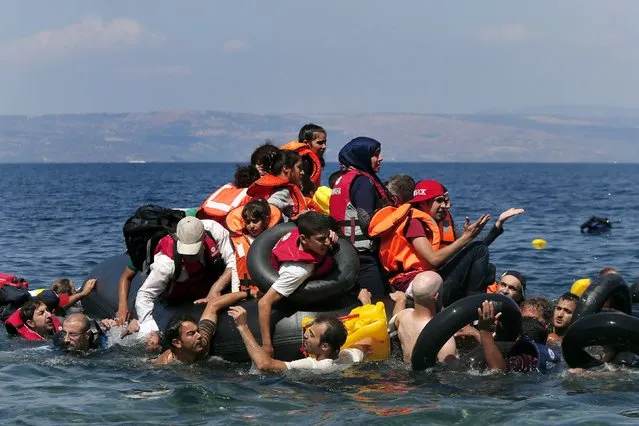 Syrian and Afghan refugees are seen on and around a dinghy that deflated some 100m away before reaching the Greek island of Lesbos, September 13, 2015. (Photo by Alkis Konstantinidis/Reuters)