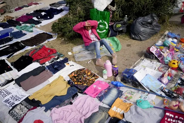 A vendor sits surrounded by her secondhand garments displayed at a market where people can buy or barter goods, on the outskirts of Buenos Aires, Argentina, Wednesday, August 10, 2022. Argentina has one of the world’s highest inflation rates, currently running at more than 60% annually, according to the National Institute of Statistics and Census of Argentina (INDEC). (Photo by Natacha Pisarenko/AP Photo)