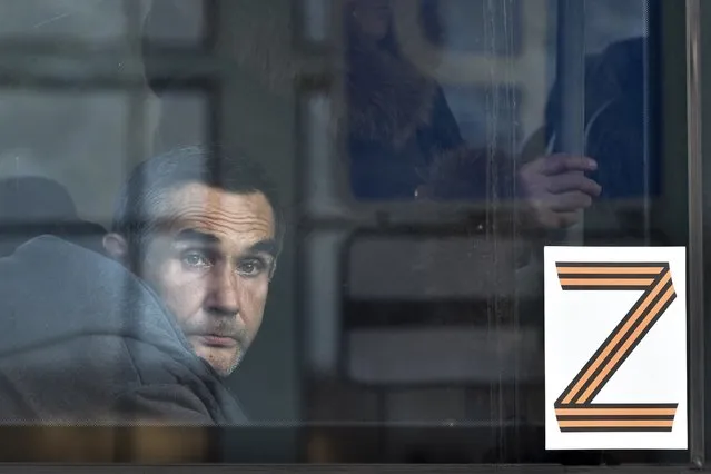 A man, an evacuee from Kherson, looks through a bus window decorated with the letter Z, which has become a symbol of the Russian military, at the railway station in Dzhankoi, Crimea, on Wednesday, November 2, 2022. (Photo by AP Photo/Stringer)