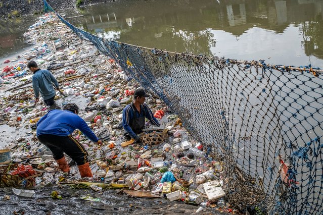 Workers clean up a river filled with trash and plastic waste in Denpasar, Bali, Indonesia, 18 March 2025. Plastic waste and trash that is carried away from residential areas wash up on the river and end up polluting the surrounding beaches and Bali Sea. (Photo by Made Nagi/EPA/EFE)