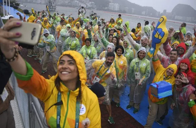 A volunteer takes a selfie photo with her fellow volunteers as they sing and dance at the Lagoa stadium following the cancellation of today's rowing competition, due to bad weather, during the Rio 2016 Olympic Games in Rio de Janeiro on August 10, 2016. (Photo by Damien Meyer/AFP Photo)