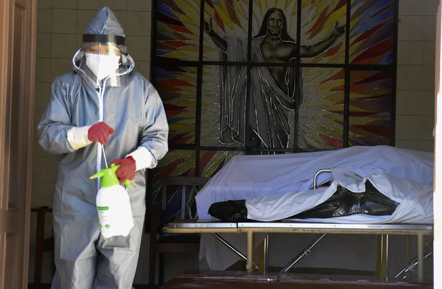 A health worker disinfects the area next to a coffins with the remains of a recently deceased resident of the San Jose nursing home in Cochabamba, Bolivia, Thursday, July 16, 2020. According to city officials, ten elder residents of the care facility have died in the last two weeks after COVID-19 related symptoms. (Photo by Dico Solis/AP Photo)