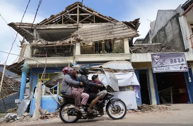 People ride a motorbike past a building damaged in Monday's earthquake in Cianjur, West Java, Indonesia, Tuesday, November 22, 2022. Rescuers on Tuesday struggled to find more bodies from the rubble of homes and buildings toppled by an earthquake that killed a number of people and injured hundreds on Indonesia's main island of Java. (Photo by Tatan Syuflana/AP Photo)