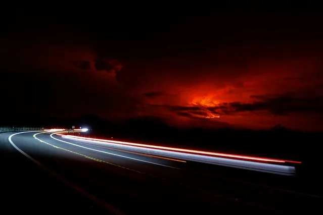 In this long camera exposure, cars drive down Saddle Road as Mauna Loa erupts in the distance, Monday, November 28, 2022, near Hilo, Hawaii. Mauna Loa, the world's largest active volcano erupted Monday for the first time in 38 years. (Photo by Marco Garcia/AP Photo)