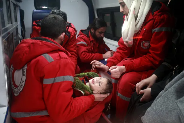 Syrian staff from the International Committee of the Red Cross evacuate a baby in Douma in the eastern Ghouta region on the outskirts of the capital Damascus on December 26, 2017. Aid workers have begun evacuating emergency medical cases from Syria's besieged rebel bastion of Eastern Ghouta, the International Committee of the Red Cross said, after months of waiting during which the UN said at least 16 people had died. Eastern Ghouta is one of the last remaining rebel strongholds in Syria and has been under a tight government siege since 2013, causing severe food and medical shortages for some 400,000 residents. (Photo by Abdulmonam Eassa/AFP Photo)