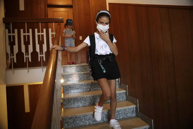 Ten-year-old Cecilia Rungi leads her four-year-old sister Camilla as they leave home to head to school in Codogno, Italy, Monday, September 14, 2020. The morning bell Monday marks the first entrance to the classroom for the children of Codogno since Feb. 21, when panicked parents were sent to pick up their children after the northern Italian town gained notoriety as the first in the West to record local transmission of the coronavirus. (Photo by Luca Bruno/AP Photo)