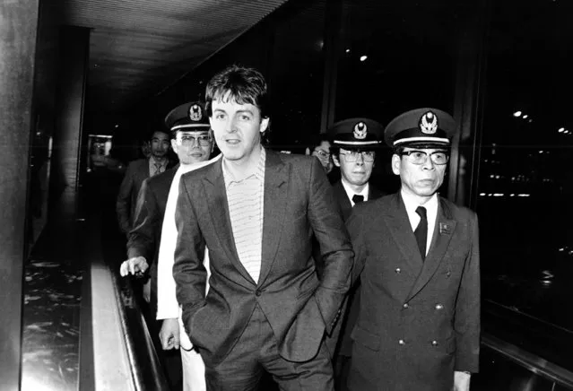 Former Beatle Paul McCartney is escorted by airport guardmen as he walks to board a plane at New Tokyo International Airport, Friday night, on January 25, 1980.  McCartney was freed from jail after the Tokyo Prosecutor's Office announced it had dropped its investigation of McCartney for drug law violations and would deport him from the country. (Photo by AP Photo)