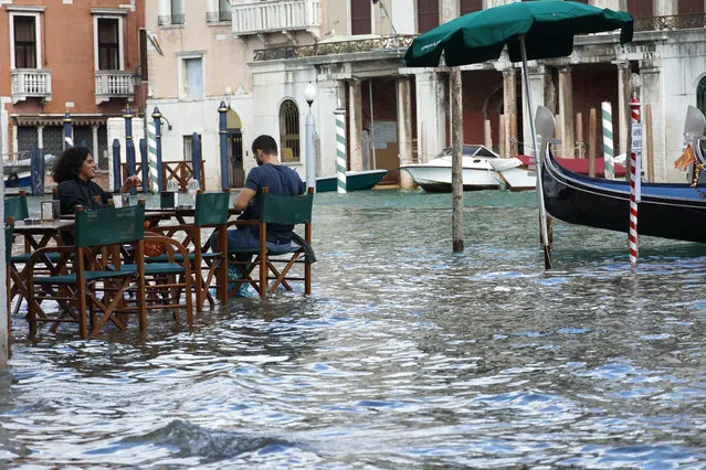 Tourists have a drink while sitting at the table of an overflooded street cafe in Riva dell'Erbaria in Rialto, while the waters of the canali rise, in Venice, Italy, 04 October 2020. The Mose flood protection system for the city of Venice and the Venetian Lagoon,i first time the day before, reportedly was not raised on 04 October. (Photo by Andrea Merola/EPA/EFE)