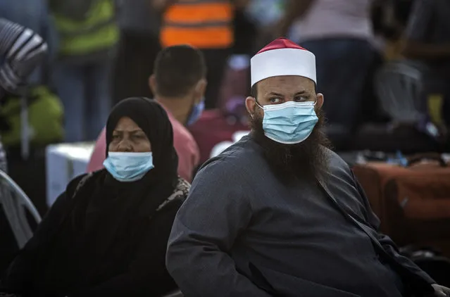 Palestinians wearing face masks sit next to their luggage, as they wait to cross to the Rafah crossing border with Egypt, southern Gaza Strip, Sunday, September 27, 2020. (Photo by Khalil Hamra/AP Photo)