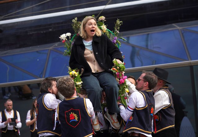 Members of the Blackheath Morris Men lift Poppy Trevillion, from London, as they perform the ancient ritual of chair-lifting – sitting a person on a florally-festooned chair and raising them above their shoulders – at the Cutty Sark in Greenwich, London on Monday, April 1, 2024. (Photo by Yui Mok/PA Images via Getty Images)