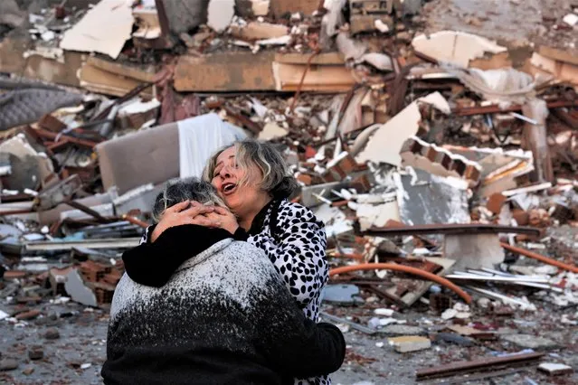 A woman reacts while embracing another person, near rubble following an earthquake in Hatay, Turkey on February 7, 2023. (Photo by Umit Bektas/Reuters)