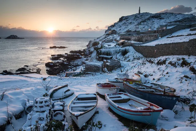 The sun sets as snow covers fishing boats left at Priest's Cove at Cape Cornwall near Penzance on February 28, 2018 in Cornwall, England. Freezing weather conditions dubbed the “Beast from the East” has brought snow and sub-zero temperatures to many parts of the UK. Amber warnings are in place in northern England, the East Midlands, London, the d south-east of England. Scotland's weather warning has been upgraded to red, which meansby. (Photo by Matt Cardy/Getty Images)