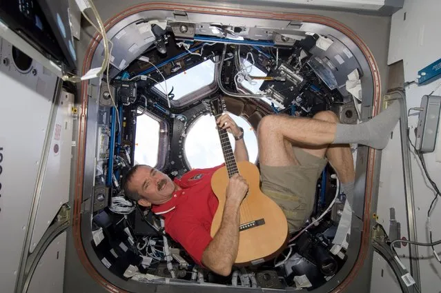 Canadian Space Agency astronaut Chris Hadfield strums his guitar in the International Space Station's Cupola on December 25, 2012, in this NASA handout image. (Photo by Reuters/NASA)