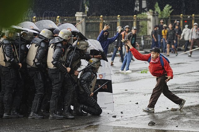 A protester throws rock at riot police officers during a protest against lavish allowances given to parliament members, in Jakarta, Indonesia, Thursday, August 28, 2025. (Photo by Achmad Ibrahim/AP Photo)