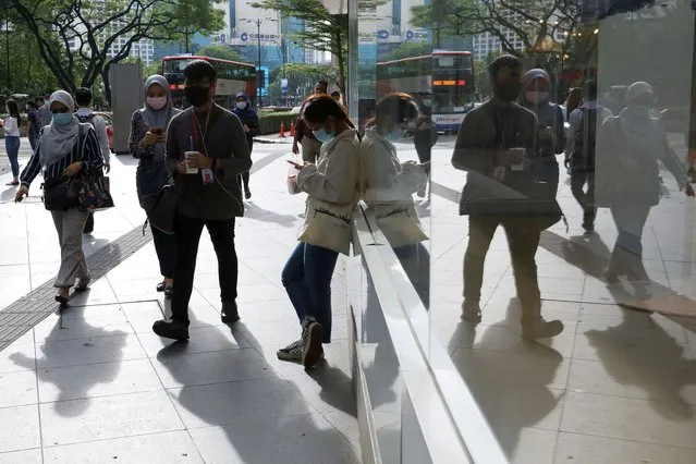 People wearing protective masks are reflected in a glass as they walk outside a shop, amid the coronavirus disease (COVID-19) outbreak in Kuala Lumpur, Malaysia on October 2, 2020. (Photo by Lim Huey Teng/Reuters)