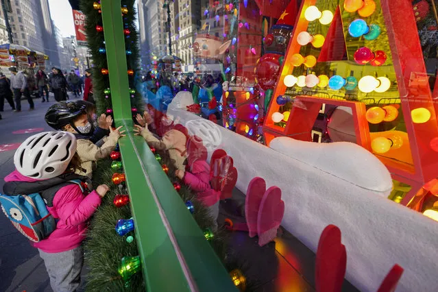 Children inspect the holiday windows display at the Macy's flagship store, Friday, November 20, 2020, in New York. Macy's 2020 holiday windows honors essential workers and first responders during the coronavirus pandemic. (Photo by Mary Altaffer/AP Photo)