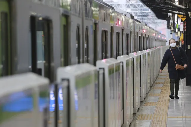 A woman wearing a face mask to protect against the spread of the coronavirus walks along a platform at the train station in Tokyo, Wednesday, November 25, 2020. (Photo by Koji Sasahara/AP Photo)