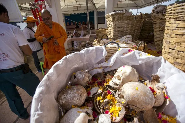 A buddhist monk sprays holy water on skulls and skeletons of unclaimed bodies during a buddhist ceremony at the Poh Teck Tung Foundation Cemetery in Samut Sakhon province, Thailand November 11, 2015. (Photo by Athit Perawongmetha/Reuters)
