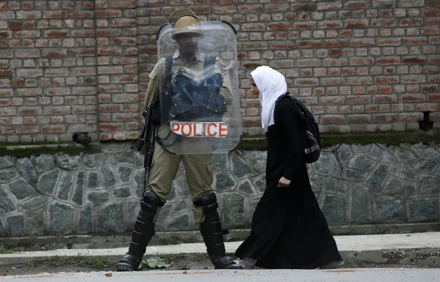 A Kashmiri Muslim student walks past an Indian policeman during a protest against recent cases of rape in the country, in Srinagar, Indian controlled Kashmir, Wednesday, April 18, 2018. Fresh rounds of protests are being seen across the country, triggered by the rape and murder of an 8-year-old girl in the Indian-controlled portion of Kashmir and the abduction and rape of a teenage girl in India's northern Uttar Pradesh state. (Photo by Mukhtar Khan/AP Photo)