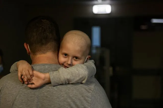 A child patient, whose leukemia treatment is underway, hugs his father as they walk along the hallways of the basement floor of Okhmadet Children's Hospital, as Russia's invasion of Ukraine continues, in Kyiv, Ukraine on February 28, 2022. (Photo by Umit Bektas/Reuters)