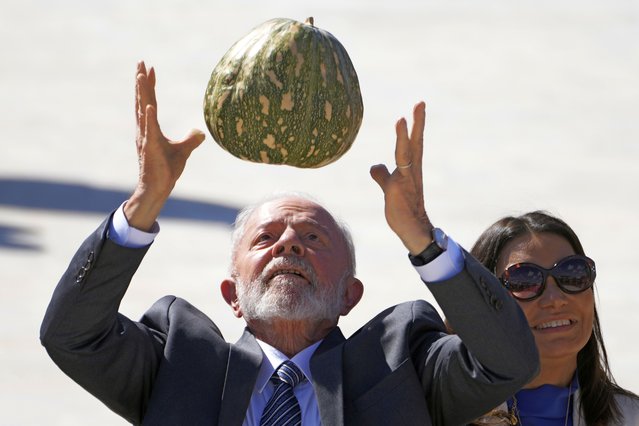 Brazil's President Luiz Inácio Lula da Silva tosses a pumpkin in the air, accompanied by first lady Rosangela da Silva known as Janja, during the Harvest Plan presentation at the Planalto Presidential Palace, in Brasilia, Brazil, July 3, 2024. (Photo by Eraldo Peres/AP Photo)