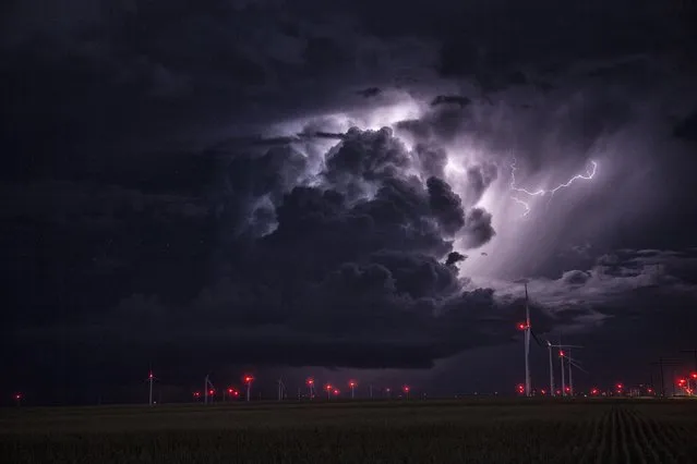 Lightning strikes in a black thunderstorm over wind turbines, on September 22, 2014, in Kansas. (Photo by Roger Hill/Barcroft Media)