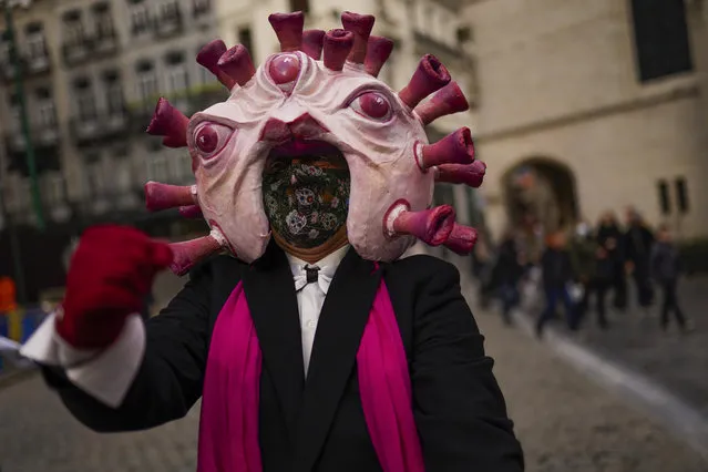 An actor, dressed up depicting a coronavirus, gestures to passers-by during a street performance promoting anti COVID-19 security measures in downtown Brussels, Thursday, December 31, 2020. (Photo by Francisco Seco/AP Photo)