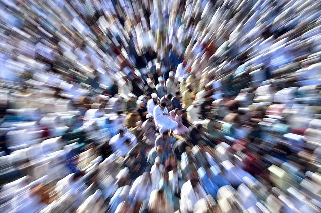 A slow shutter speed with zoom effect shows Pakistani Muslims performing Eid al-Fitr prayer in Karachi, Pakistan, 22 April 2023. The beginning of Eid al-Fitr, which is determined by sighting of the new moon, was marked on 21 April in several countries while some countries are celebrating the three-day festival marking the end of Ramadan starting from 22 April. (Photo by Shahzaib Akber/EPA)
