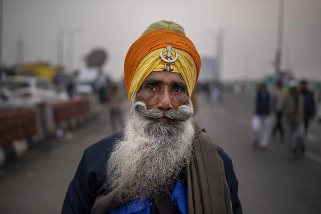 A Sikh farmer listens to a speaker from a distance as they block a major highway in a protest against new farm laws while it rains at the Delhi-Uttar Pradesh state border, India, Monday, January 4, 2021. Ignoring the coronavirus pandemic, the farmers have been blockading highways connecting New Delhi to northern India for nearly five weeks, obstructing transportation and dealing a blow to manufacturing and businesses in the north. (Photo by Altaf Qadri/AP Photo)