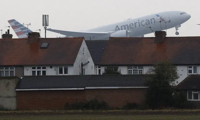 An airplane takes off over the rooftops of nearby houses at Heathrow Airport in Harmondsworth, London, Tuesday, October 25, 2016. Britain's government gave the go-ahead Tuesday to build a new runway at London's Heathrow airport despite concerns about air pollution, noise and the destruction of homes in the capital's densely populated western neighborhoods. (Photo by Frank Augstein/AP Photo)