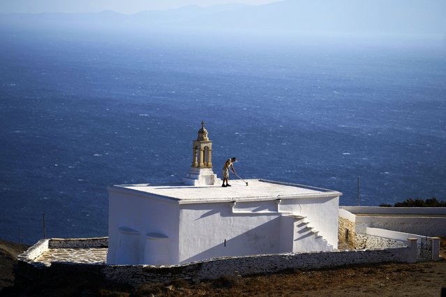 Naim Domi, 50, an Albanian worker who has lived in Greece for 17 years, paints the rooftop of the Panagia Faneromeni family-owned chapel overlooking the Aegean Sea near the village of Pyrgos, on the island of Tinos, Greece, Sunday, September 7, 2025. (Photo by Petros Giannakouris/AP Photo)