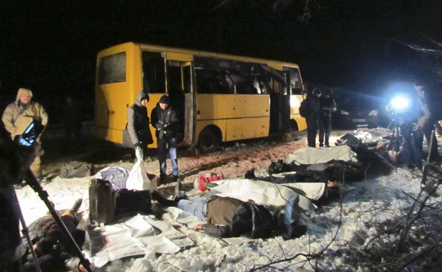 In this picture taken late Tuesday, January 13, 2015, the bodies of the victims of a shelling attack on a passenger bus near the eastern Ukraine town of Volnovakha are laid out by the side of the road. In the single largest loss of life so far this year, civilians traveling on a commuter bus from Donetsk were killed Tuesday afternoon by what Ukrainian say were rockets fired from a Grad launcher in rebel territory. (Photo by Mykola Ryabchenko/AP Photo)