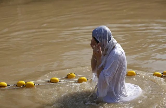 A Christian pilgrim dips in the water after a ceremony at the baptismal site known as Qasr el-Yahud on the banks of the Jordan River near the West Bank city of Jericho January 18, 2015. Orthodox Christians flocked to the Jordan River to celebrate the feast of the Epiphany at the traditional site where it is believed John the Baptist baptised Jesus. (Photo by Mohamad Torokman/Reuters)