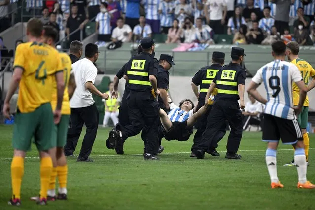A pitch invader is escorted by security personnel during a friendly football match between Australia and Argentina at the Workers' Stadium in Beijing on June 15, 2023. (Photo by Wang Zhao/AFP Photo)
