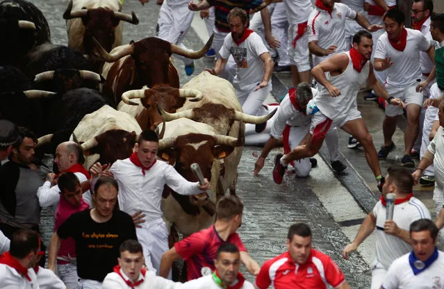 Revellers sprint in front of bulls and steers during the first running of the bulls of the San Fermin festival in Pamplona, Spain, July 7, 2018. (Photo by Vincent West/Reuters)