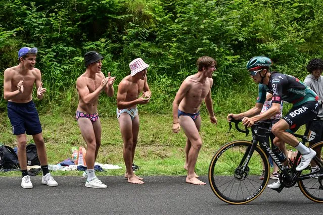 Scantily clad spectators cheer as BORA - hansgrohe's Australian rider Jai Hindley cycles in the final kilometers of the 5th stage of the 110th edition of the Tour de France cycling race, 163 km between Pau and Laruns, in the Pyrenees mountains in southwestern France, on July 5, 2023. (Photo by Marco Bertorello/AFP Photo)