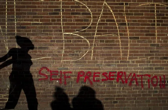 The shadow of a woman, who was taking part in a march, falls on a brick wall past a message which reads “One Baltimore, Self Preservation”, in west Baltimore, Maryland May 2, 2015. (Photo by Adrees Latif/Reuters)