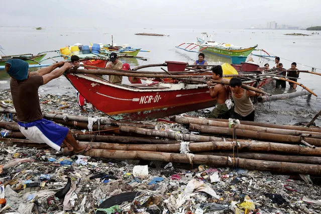 Fishermen carry their boat up on the shore after breaking off its mooring in turbulent floodwaters following overnight southwest monsoon rains brought about by a tropical storm for the second day Wednesday, July 18, 2018, in Bacoor, south of Manila, Philippines. Floodwaters have receded Wednesday in Manila but local authorities still suspended classes as well as some work in Government offices. (Photo by Bullit Marquez/AP Photo)