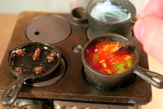 Jay cooks the ingredients of the tiny spaghetti on the tiny stove. (Photo by Jay Baron/Caters News)