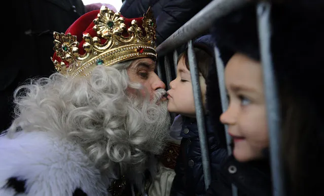 A man dressed as one of the Three Wise Men kisses a child upon arriving at Poniente beach in Gijon, Spain, January 5, 2016. (Photo by Eloy Alonso/Reuters)