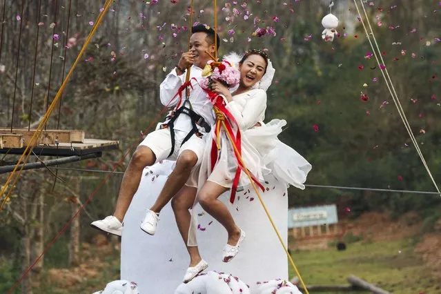 Groom Chaiyut Phuangphoeksuk and bride Prontathourn Pronnapatthun, with safety harnesses, jump from the top of a 3.5-metre tall wedding cake sculpture during their wedding ceremony at a resort in Ratchaburi province February 13, 2015. (Photo by Athit Perawongmetha/Reuters)