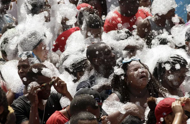 Bathed with suds, revelers dance in the street during Carnival celebrations in Panama City, Monday, February 16, 2015. (Photo by Arnulfo Franco/AP Photo)