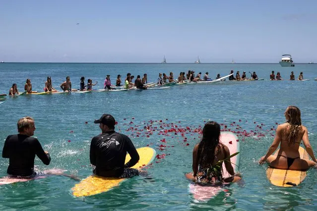 People throw flowers during a community paddle out, organized by nonprofit Na Kama Kai, for those affected by the Maui Fires at Kuhio Beach, Honolulu, Hawaii, on August 19, 2023. At least 111 people are known to have died in what was the deadliest wildfire in the US in over a century. The final toll is expected to be considerably higher. (Photo by Yuki Iwamura/AFP Photo)