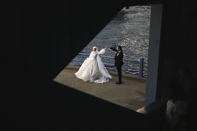 A young couple pose for a video and photo session at Galata bridge in Istanbul, Turkey, Tuesday, September 5, 2023. Galata bridge is a popular location for photograph session of couples who are about to or just married. (Photo by Francisco Seco/AP Photo)