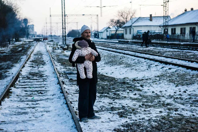A man holds his baby while waiting with other migrants and refugees at a train station for a train in southern Serbian town of Presevo on January 20, 2016. As refugees continued to flow from Greece through the Balkans on their way to western Europe, aid workers sounded alarms over inadequate shelter from the current freezing temperatures and snowy conditions, particularly for children. (Photo by Dimitar Dilkoff/AFP Photo)