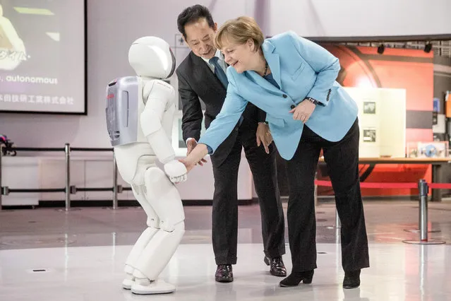 German Chancellor Angela Merkel (R) gets to know the robot Asimo (Advanced Step in Innovative Mobility) at the Miraikan Museum of Emerging Science and Innovation in Daiba, Tokyo, Japan, 09 March 2015. In center the museum's director Mamoru Mohri. Merkel is in Japan for a two-day visit.  EPA/MICHAEL KAPPELER