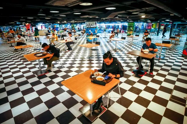 People eat lunch seated individually in the food court at an offices building in Bangkok, Thailand, 17 May 2021. Bangkok has eased COVID-19 dinning restrictions, previously allowing only take away with no dine in permitted, and now allowing one patron per table of four, spaced according to social distancing guidelines. Restaurants in dark-zones such as Bangkok, will be allowed to serve customers until 9pm, and only up to 25 percent capacity as officials try to find a balance between cover-19 preventive measures and helping businesses to remain open. (Photo by Diego Azubel/EPA/EFE)